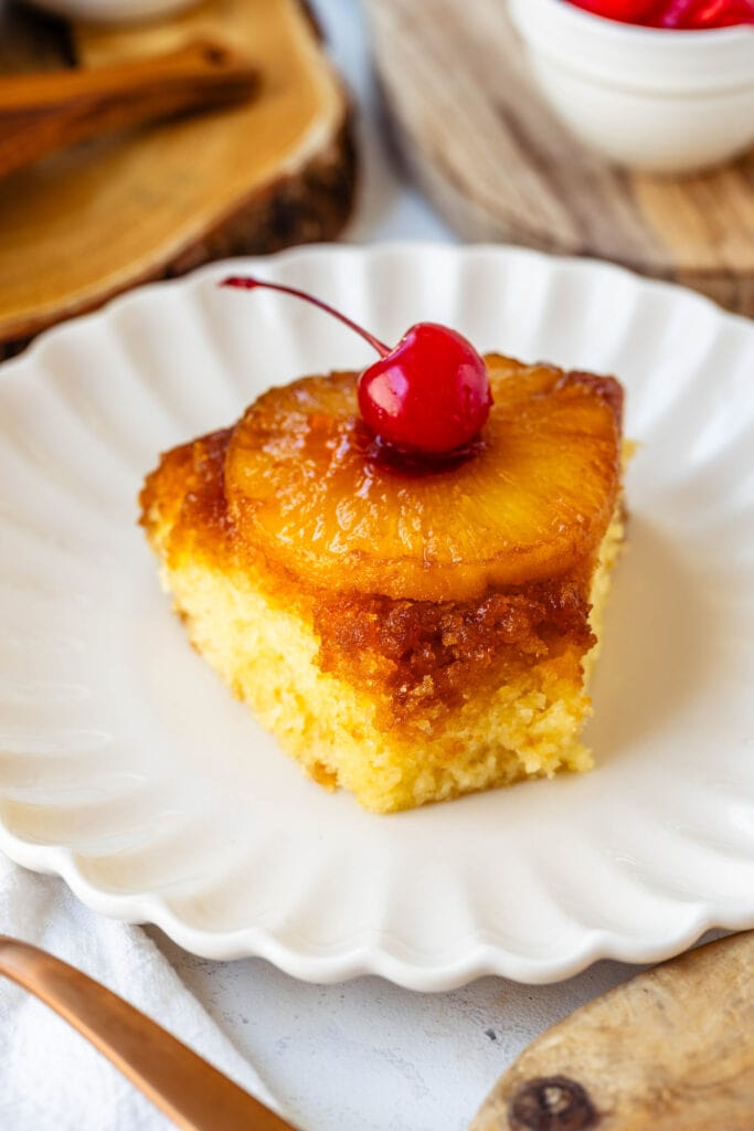 slice of pineapple upside down cake with a cherry in the center of the pineapple ring, on a plate.
