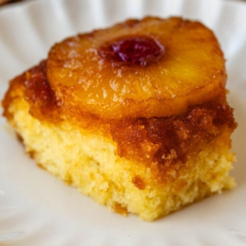 slice of pineapple upside down cake with a cherry in the center of the pineapple ring, on a plate.