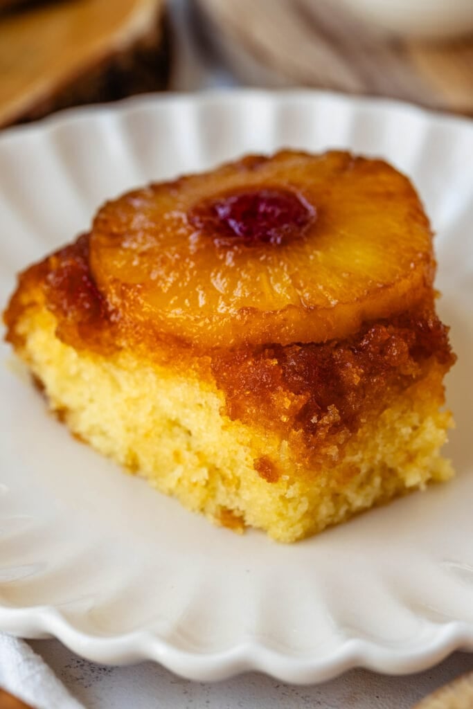 slice of pineapple upside down cake with a cherry in the center of the pineapple ring, on a plate.