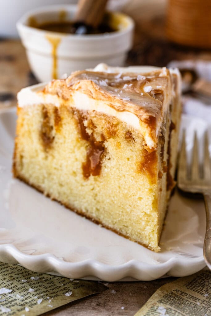 slice of caramel cake, with caramel filling, topped with cream cheese and caramel swirls.