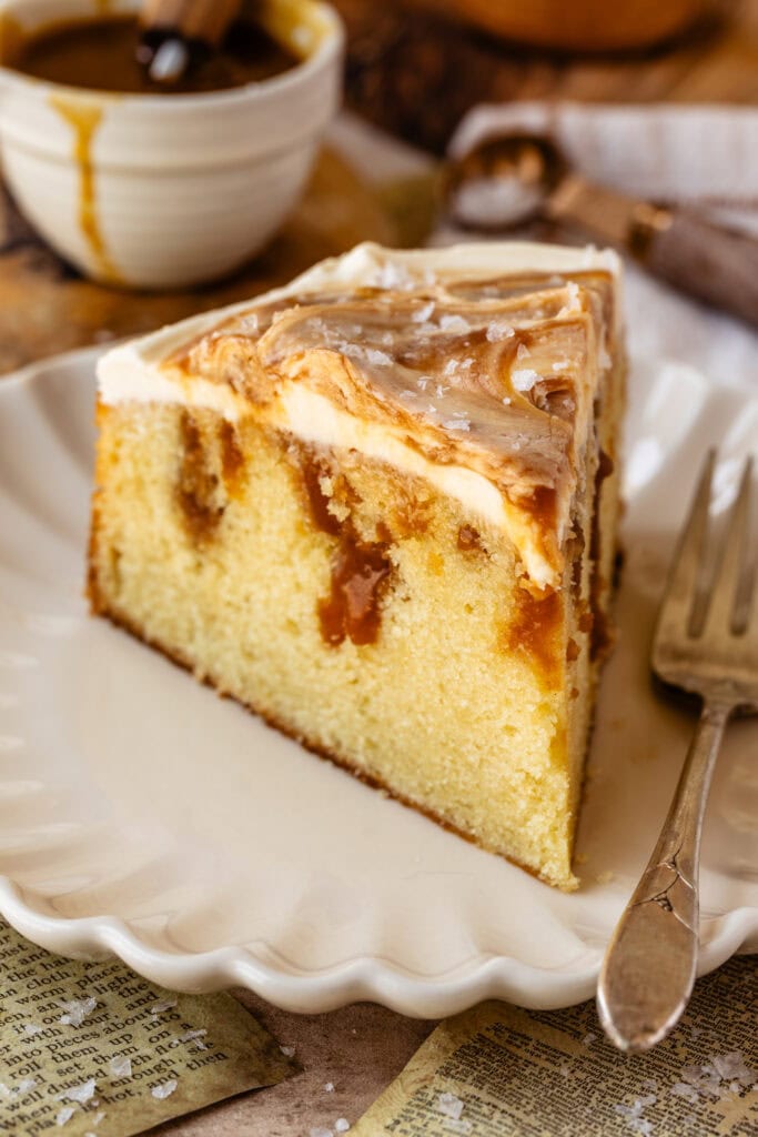 slice of caramel cake on a plate with a fork next to it.