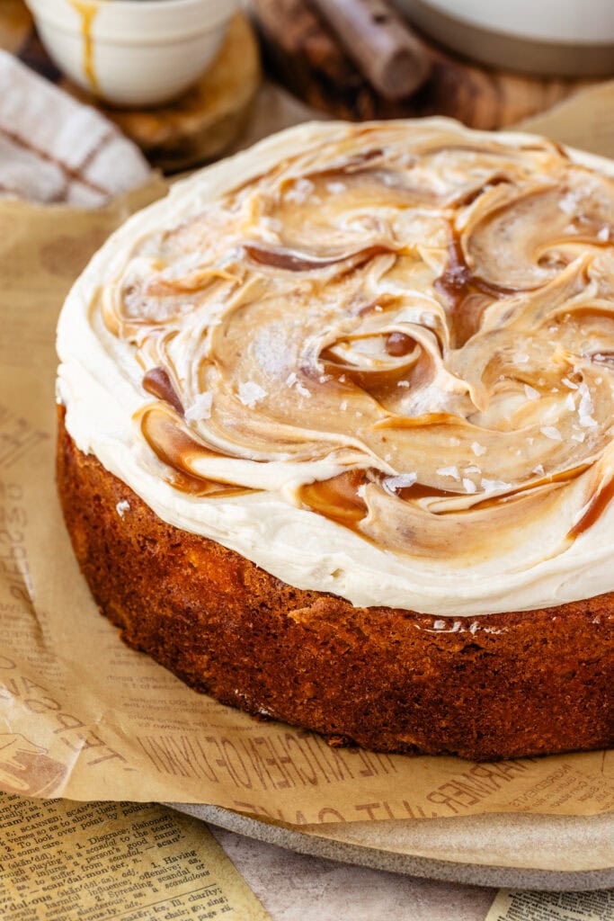 caramel cake topped with caramel swirls and cream cheese frosting on top of a plate.