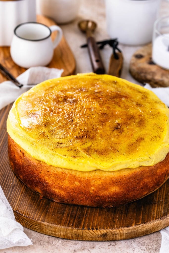 Crème Brûlée Cake with a caramelized sugar topping, and vanilla pastry cream, on top of a wooden board.