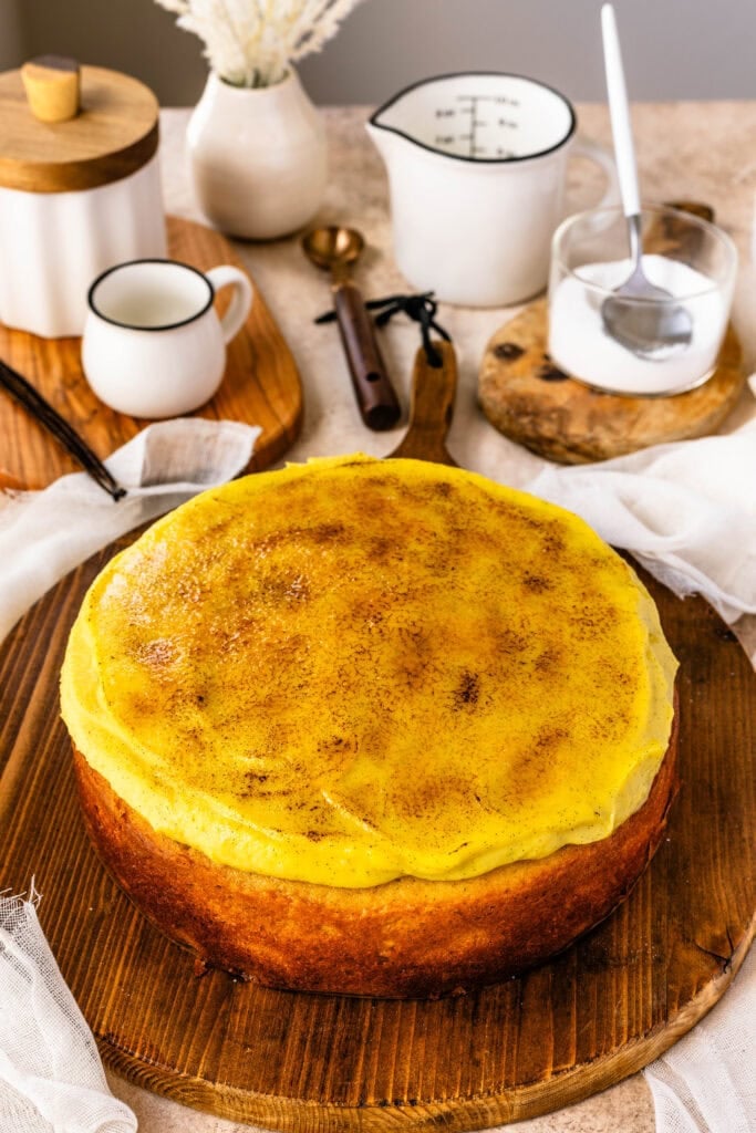 Crème Brûlée Cake with a caramelized sugar topping, and vanilla pastry cream, on top of a wooden board.