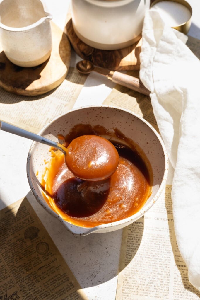 caramel sauce in a bowl with a spoon pouring caramel into the bowl.