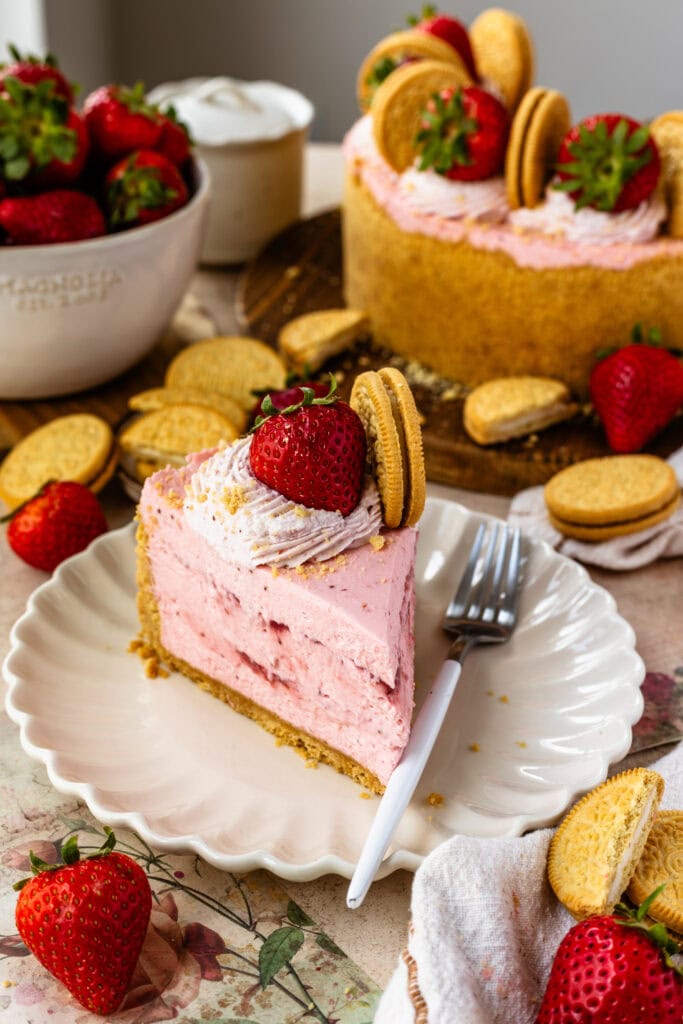 slice of strawberry cheesecake on a plate, with a strawberry cheesecake on the back.