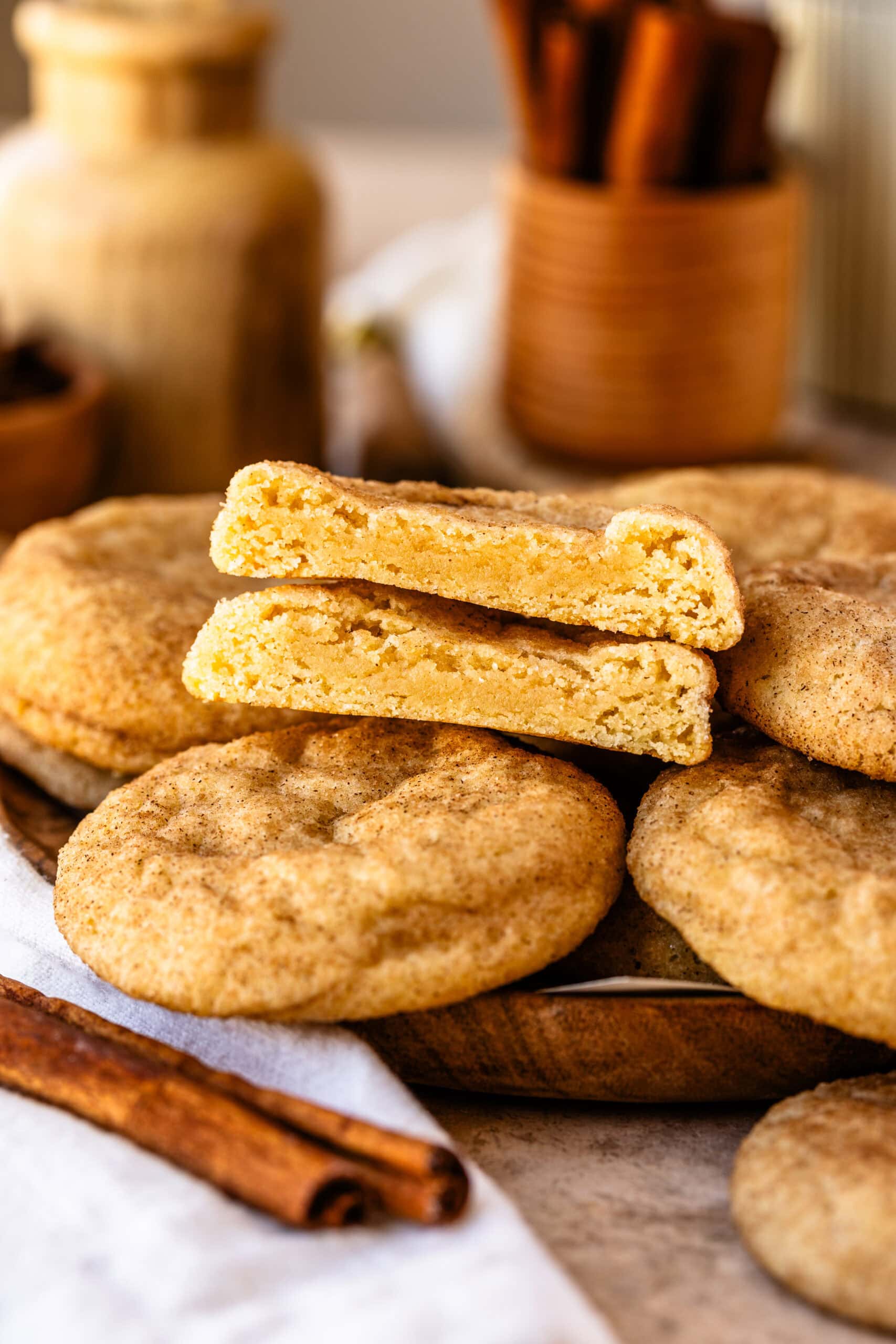 snickerdoodle cookies on a plate, with one cookie cut in half on top of the cookies.