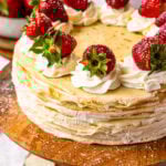 crepe cake topped with whipped cream and strawberries.