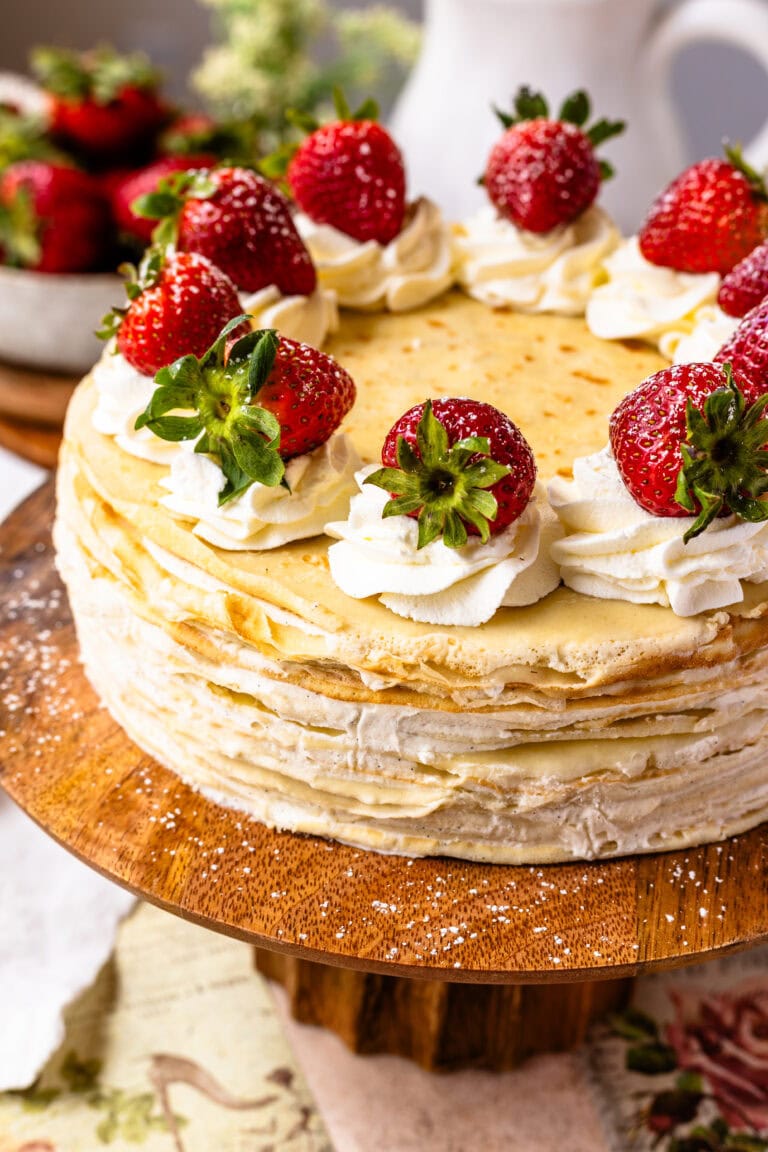 crepe cake topped with whipped cream and strawberries.