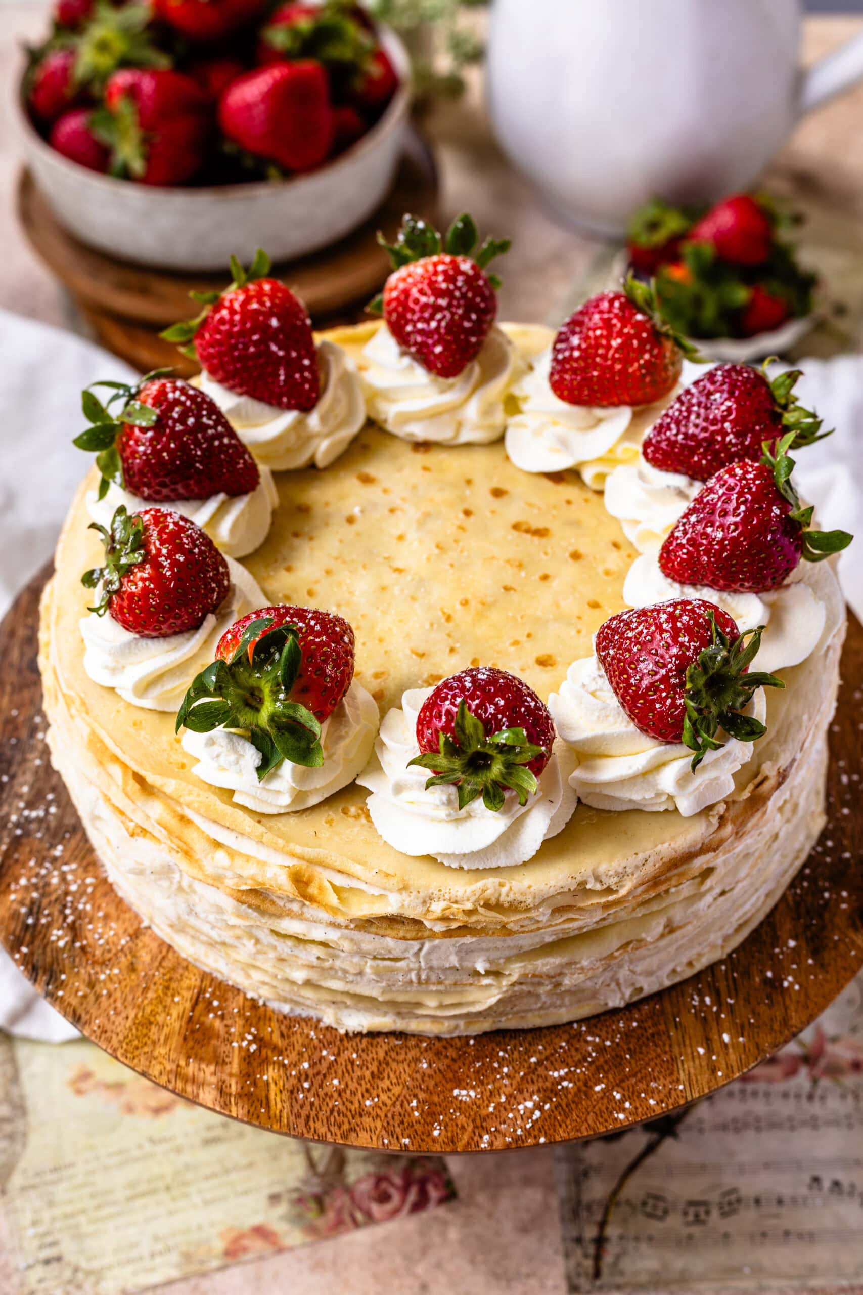 crepe cake topped with whipped cream and strawberries.