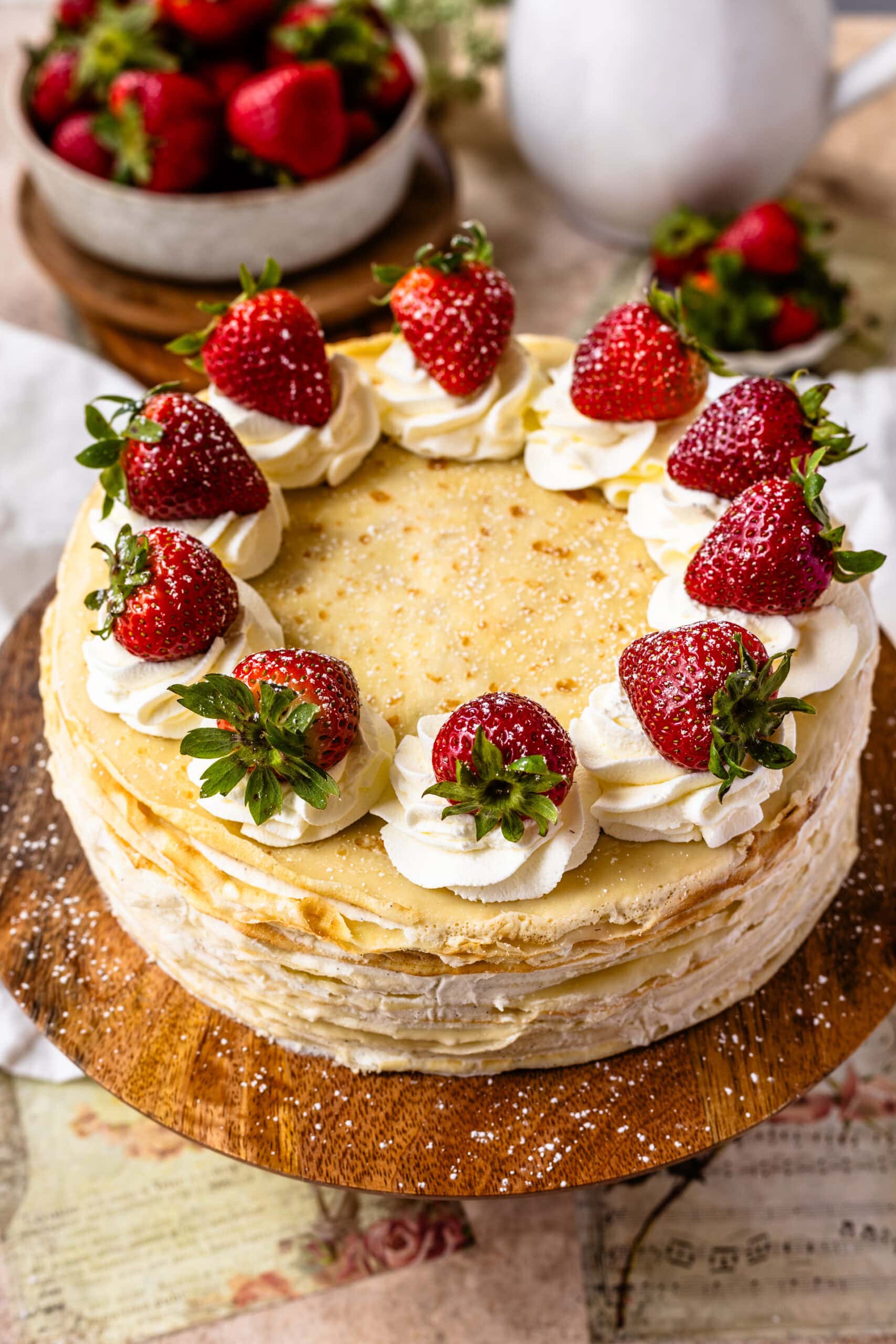 crepe cake topped with whipped cream and strawberries.