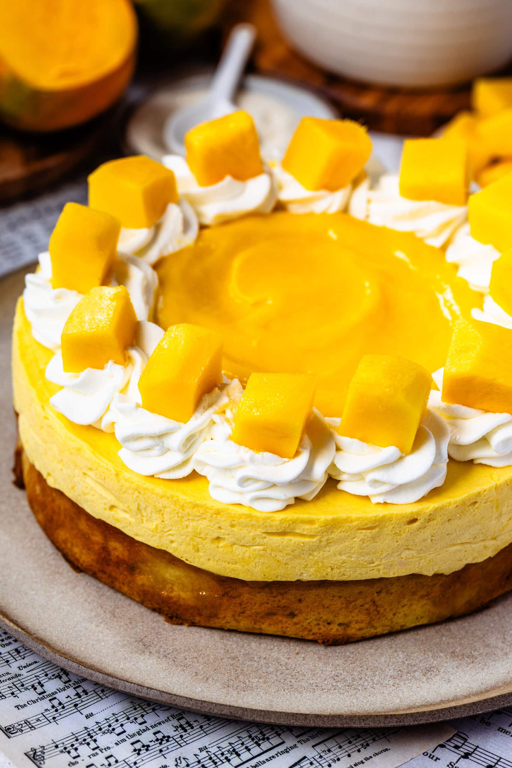 mango mousse cake topped with mango slices and whipped cream, and mango curd in the center.