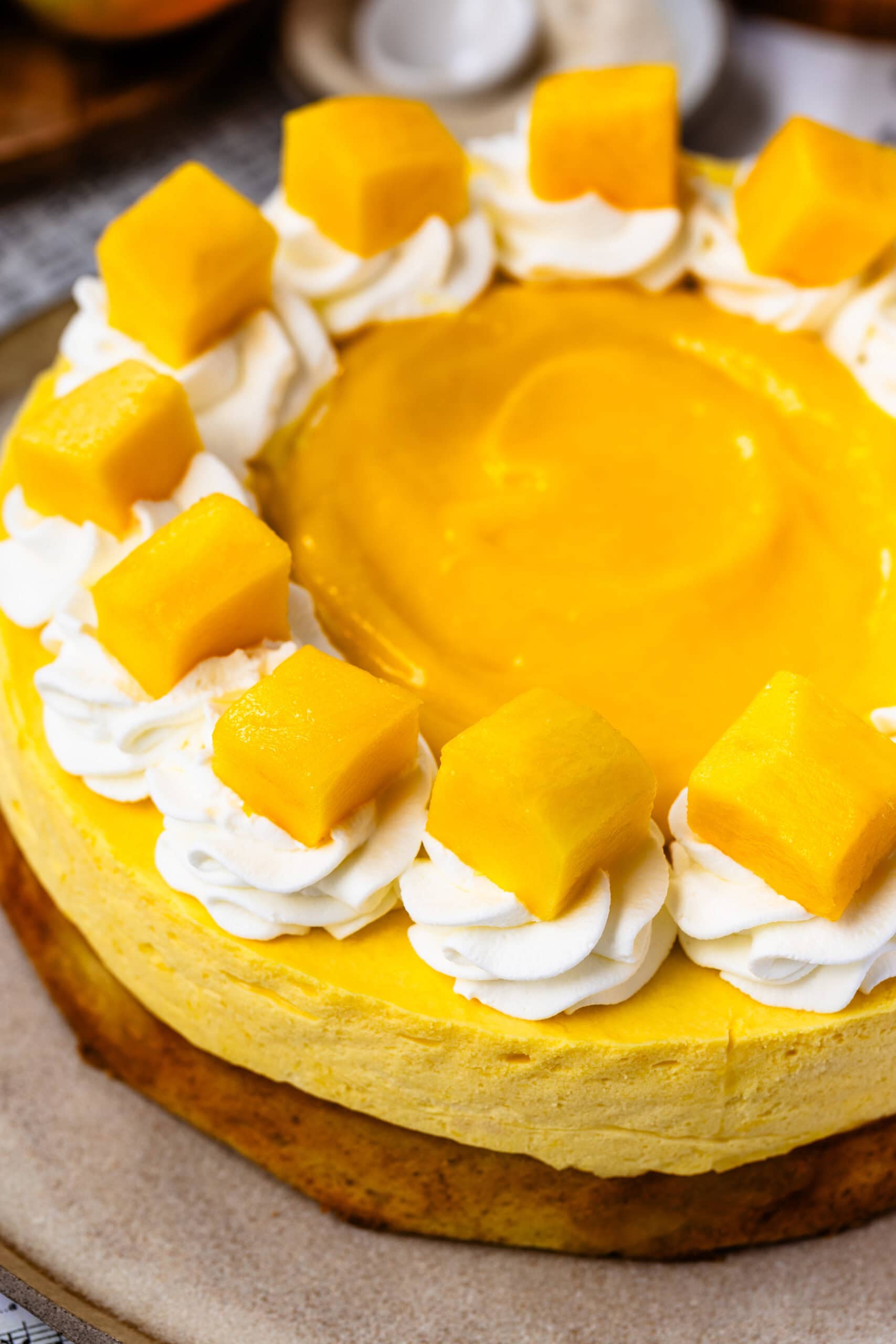 mango mousse cake topped with mango slices and whipped cream, and mango curd in the center.