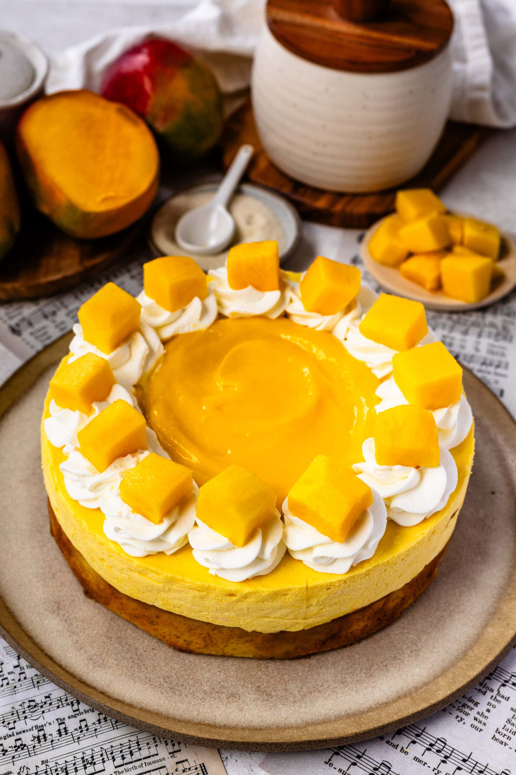 mango mousse cake topped with mango slices and whipped cream, and mango curd in the center.