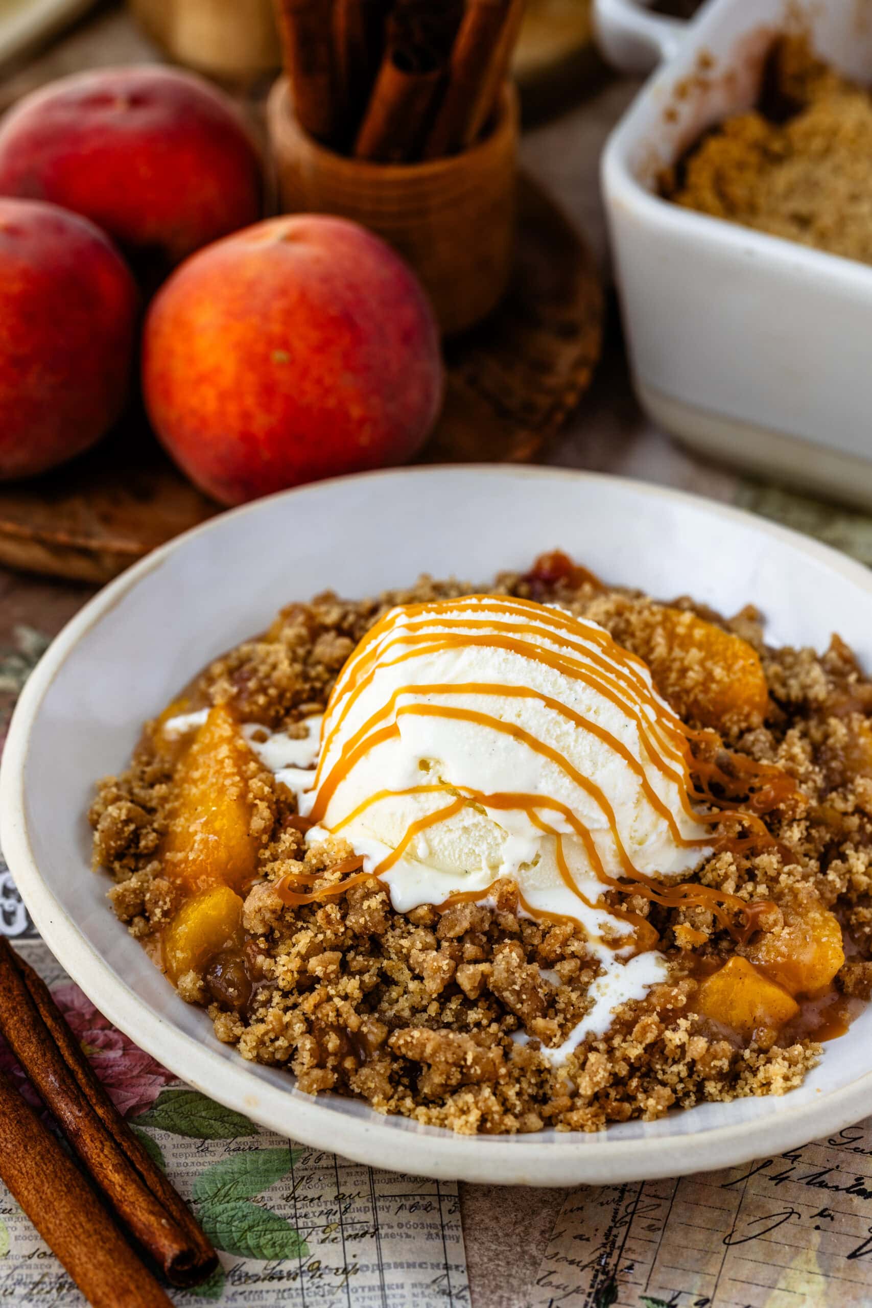 Peach Crisp with ice cream on top and caramel sauce on a bowl.