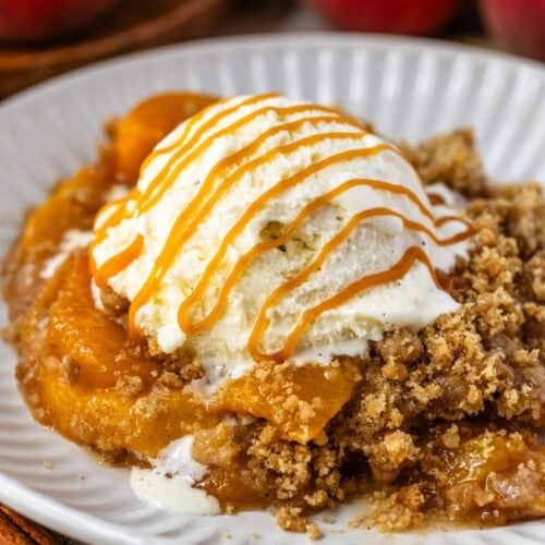 Peach Crisp with ice cream on top and caramel sauce on a bowl.