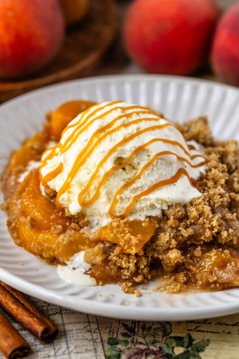 Peach Crisp with ice cream on top and caramel sauce on a bowl.