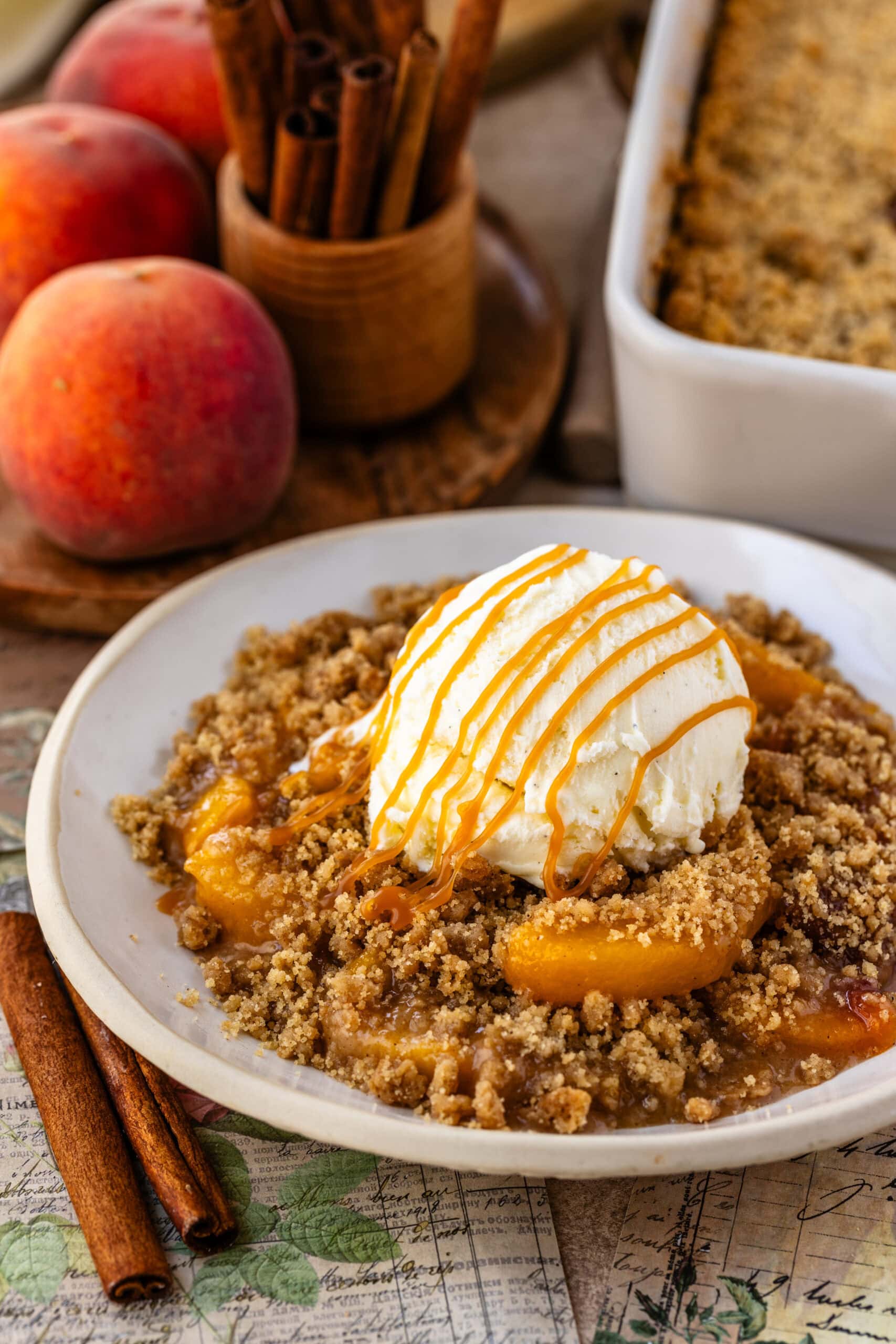 Peach Crisp with ice cream on top and caramel sauce on a bowl.