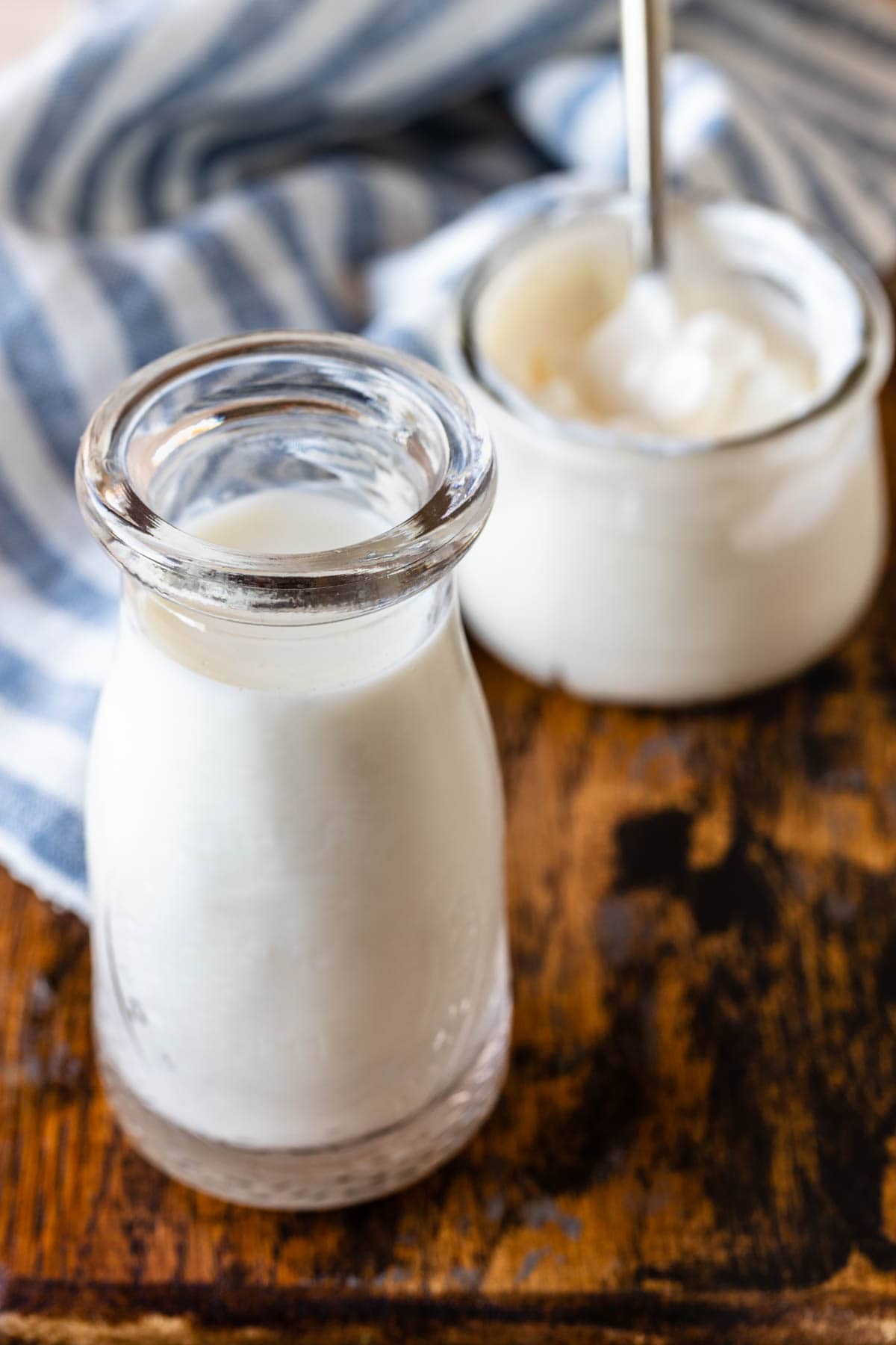 milk in a bottle with a container with yogurt in the back.