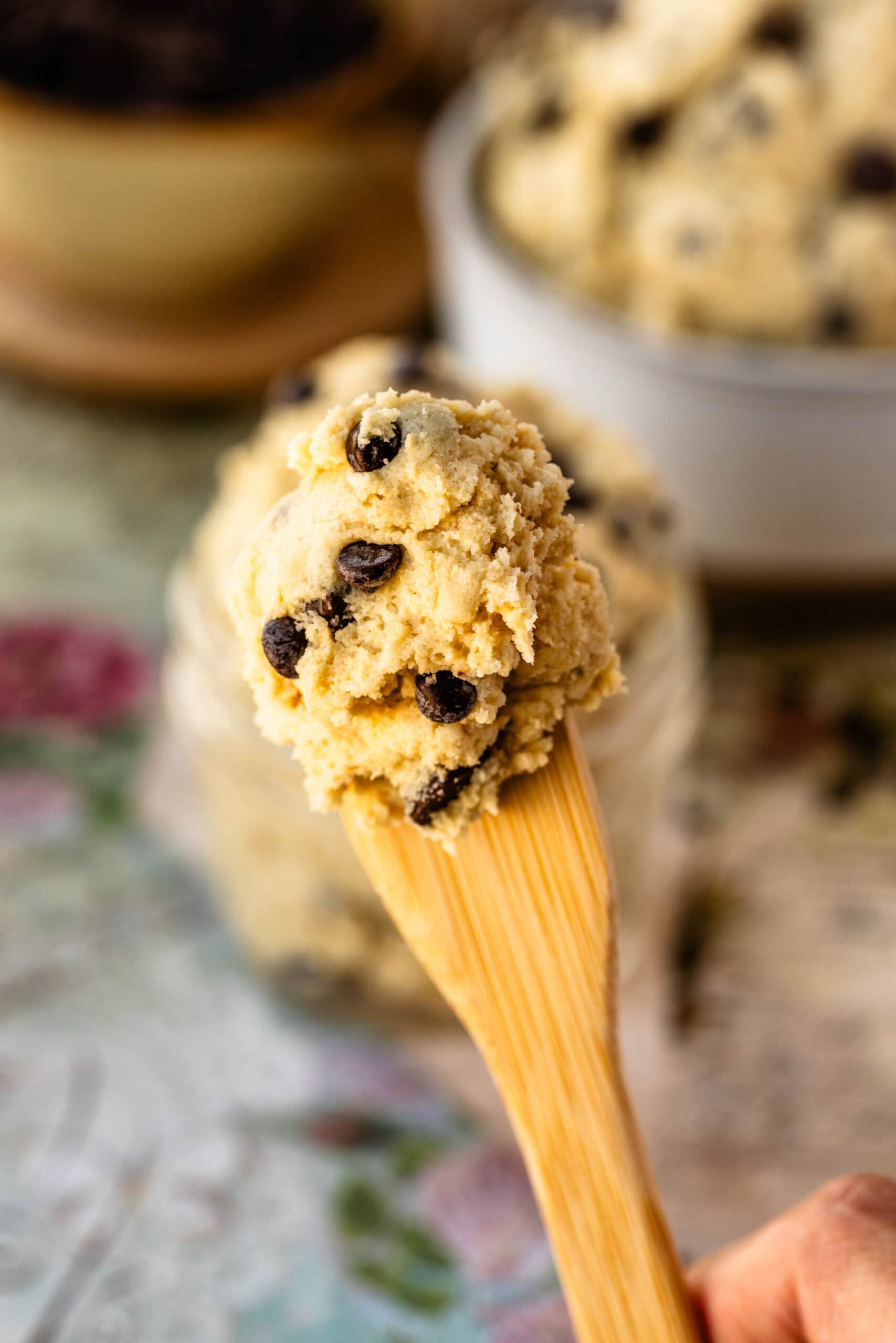 A close-up of a spoonful of edible cookie dough, loaded with chocolate chips, showcasing its creamy texture and perfect for snacking.