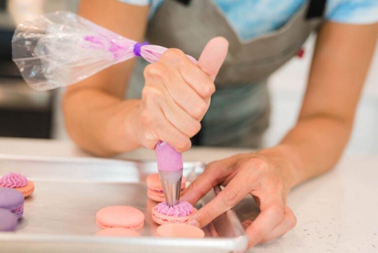 hand piping filling in the macarons.