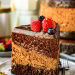 A slice of chocolate mousse cake on a plate, showcasing its rich layers of moist chocolate cake, creamy mousse, and smooth ganache, topped with fresh berries for a vibrant finish.