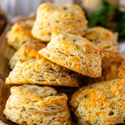 Stacked cheddar biscuits with a soft, fluffy interior and golden, cheesy layers, sprinkled with herbs.