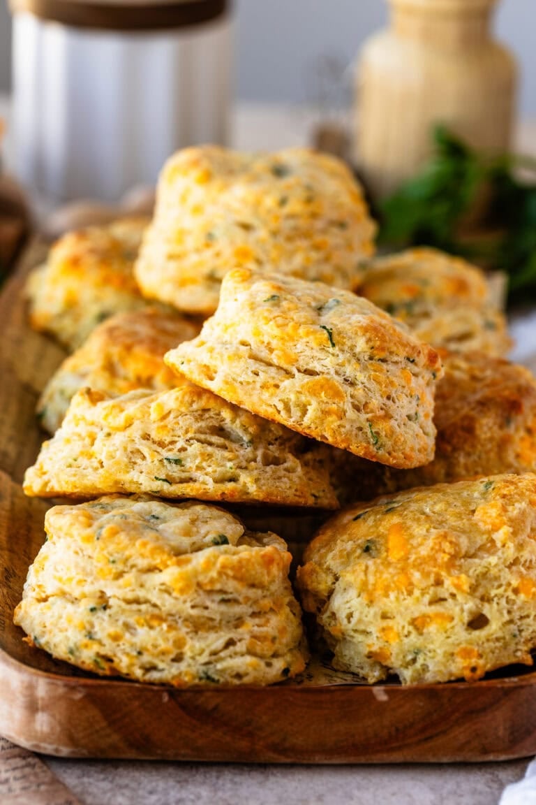 Stacked cheddar biscuits with a soft, fluffy interior and golden, cheesy layers, sprinkled with herbs.