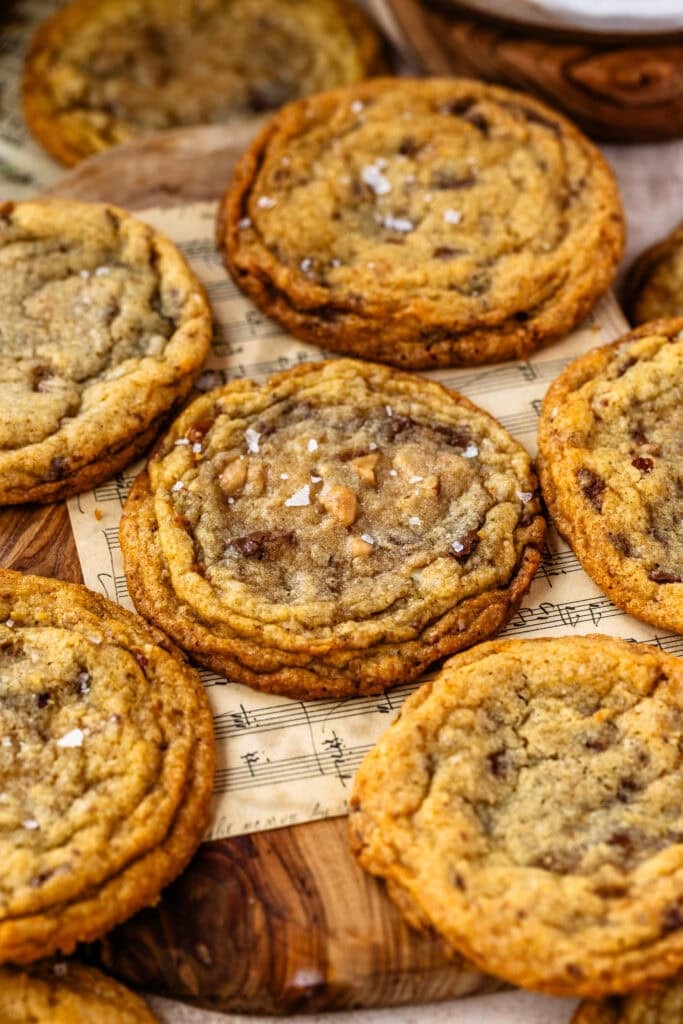 A close-up of freshly baked toffee brown butter cookies topped with flaky sea salt.