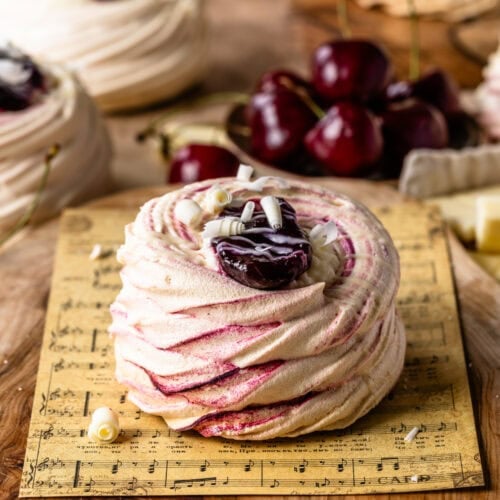 Delicate Amaretto Cherry Pavlovas with crisp, swirled meringue shells filled with cherry compote and topped with white chocolate curlsโa light, elegant dessert bursting with sweet cherry and almond flavor.