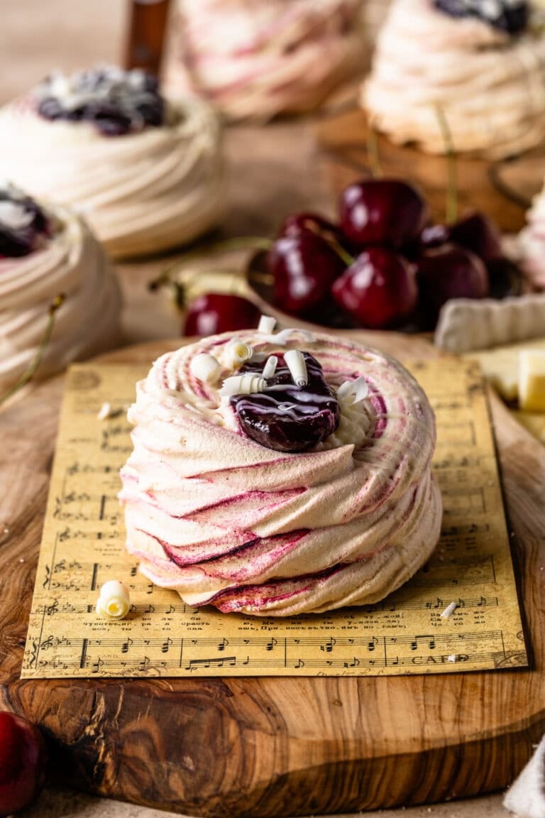 Delicate Amaretto Cherry Pavlovas with crisp, swirled meringue shells filled with cherry compote and topped with white chocolate curlsโa light, elegant dessert bursting with sweet cherry and almond flavor.