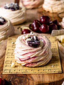 Delicate Amaretto Cherry Pavlovas with crisp, swirled meringue shells filled with cherry compote and topped with white chocolate curls—a light, elegant dessert bursting with sweet cherry and almond flavor.