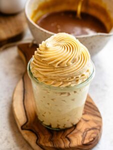 A glass jar filled with silky salted caramel buttercream, topped with a perfect swirl of frosting piped in soft caramel tones.