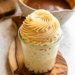 A glass jar filled with silky salted caramel buttercream, topped with a perfect swirl of frosting piped in soft caramel tones.