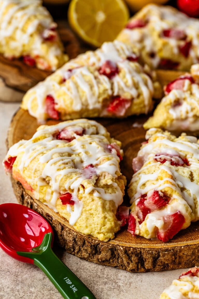 Strawberry scones with lemon glaze stacked on a wooden board.