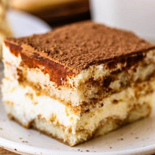 A slice of classic tiramisu with layers of espresso-soaked ladyfingers, mascarpone cream, and a cocoa-dusted top.
