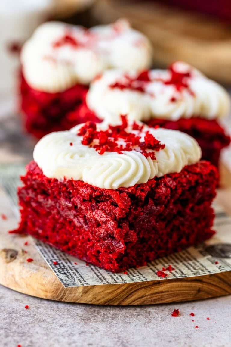 Red velvet brownie topped with cream cheese frosting and red velvet crumbs, showing a moist and fudgy interior.
