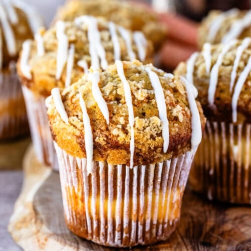 Fully finished and baked carrot cake muffins atop a wooden serving board ready to be eaten!