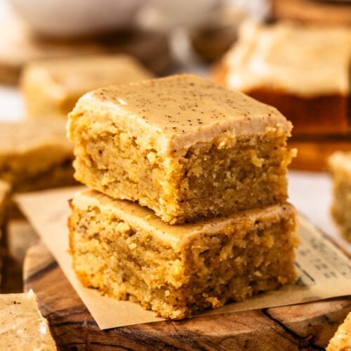 Two delicious coffee blondies stacked on top of each other on a wooden serving board.