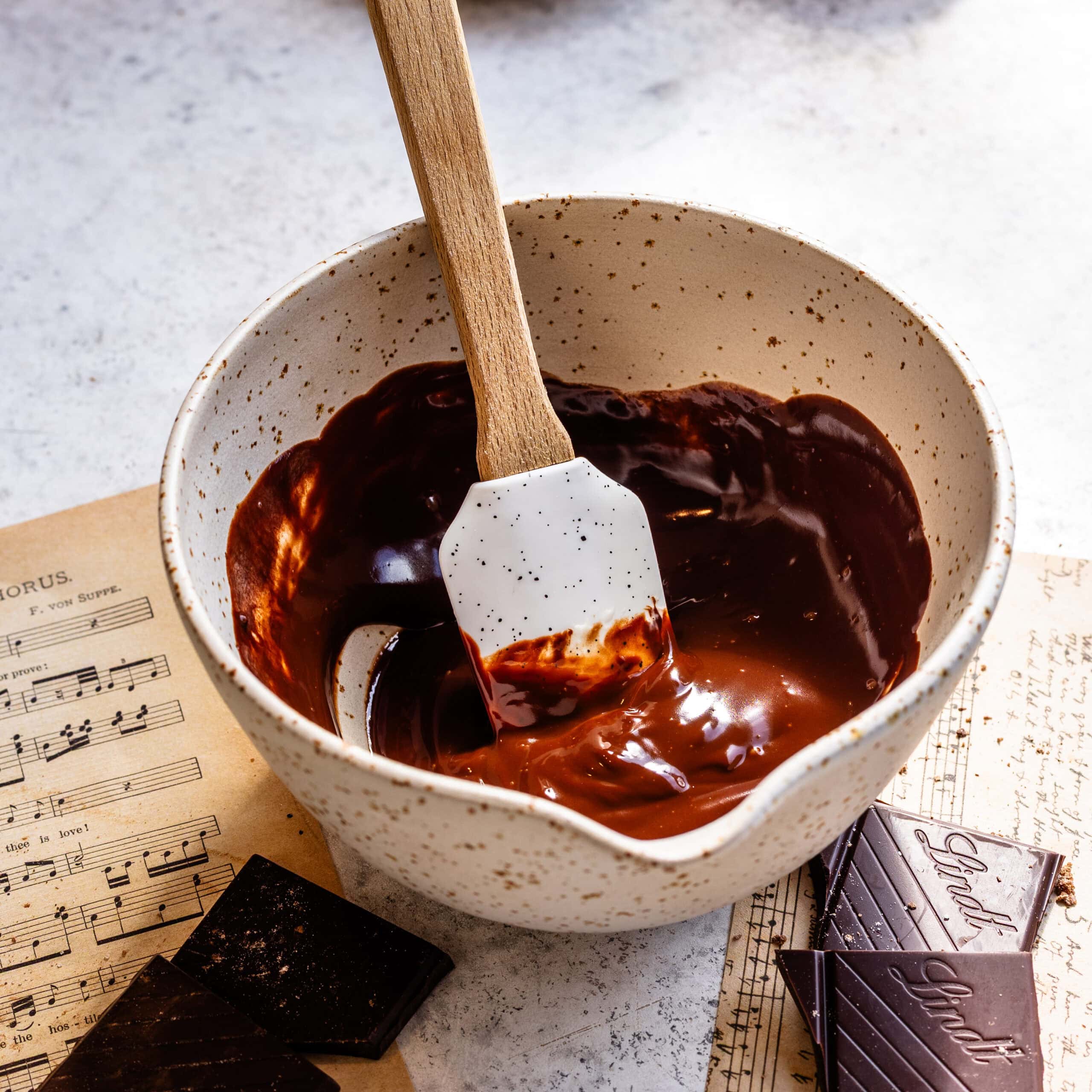 A silky chocolate ganache in a porcelain bowl, ready to be poured over delicious scones.