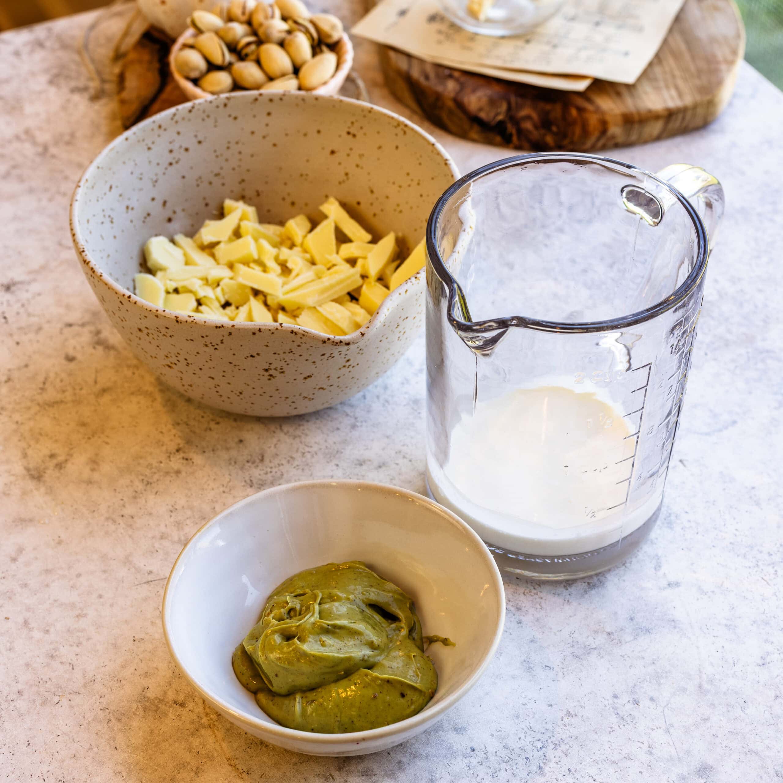 Ingredients for the white chocolate pistachio ganache neatly arranged on a granite surface.