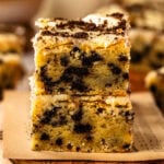 Two stacked cookies and cream blondies with oreo ganache on a wooden serving board.