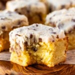 A close-up of a sliced cookie dough blondie topped with edible chocolate chip cookie dough, showing the dense chewy blondie interior and mini chocolate chips throughout.