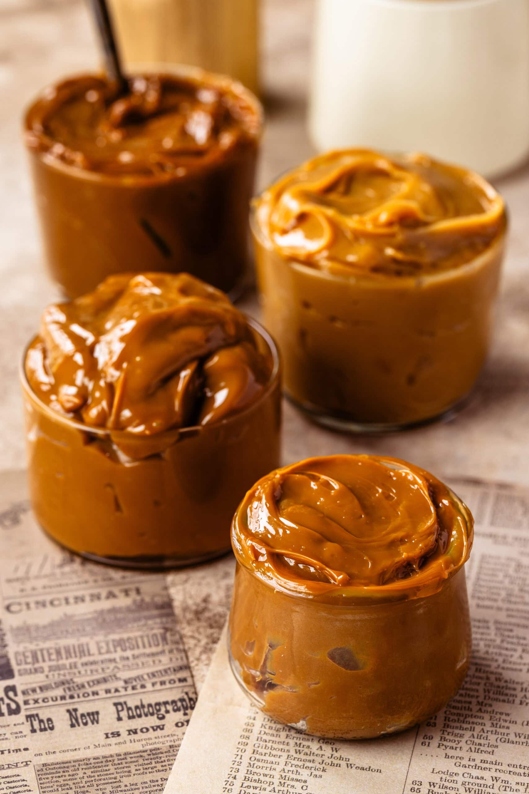 Four small jars of dulce de leche showing different rich caramel shades and thick creamy textures.