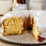 A slice removed from the glazed donut cake, revealing the soft, fluffy interior and tender texture beneath the thick vanilla glaze.