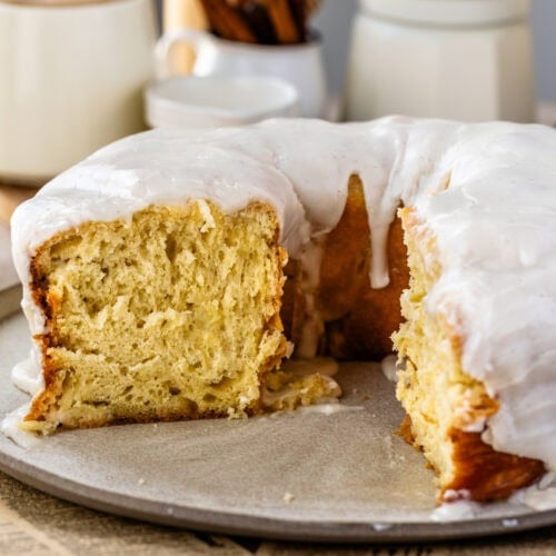 A slice removed from the glazed donut cake, revealing the soft, fluffy interior and tender texture beneath the thick vanilla glaze.