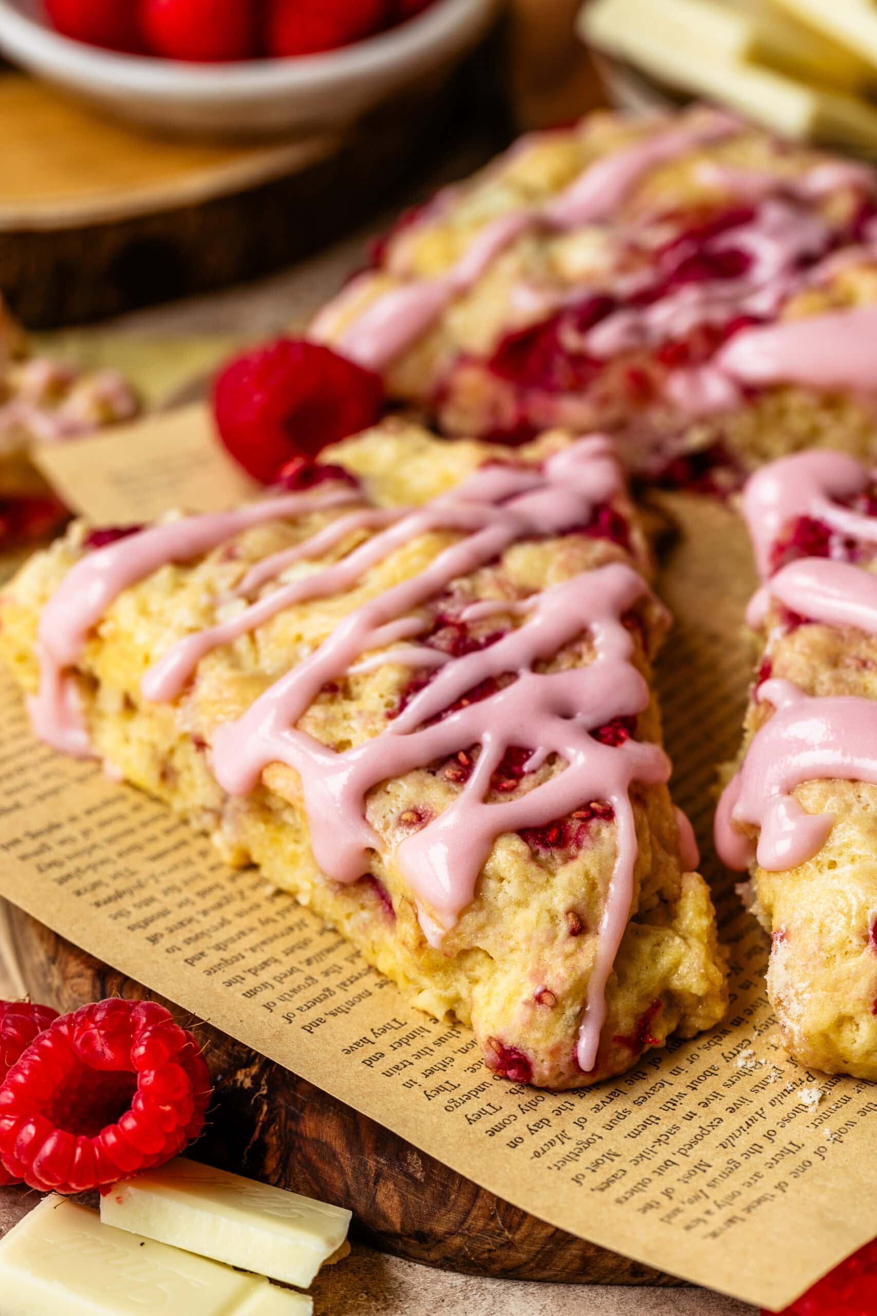 Raspberry white chocolate scones drizzled with raspberry cream cheese glaze on a serving platter.