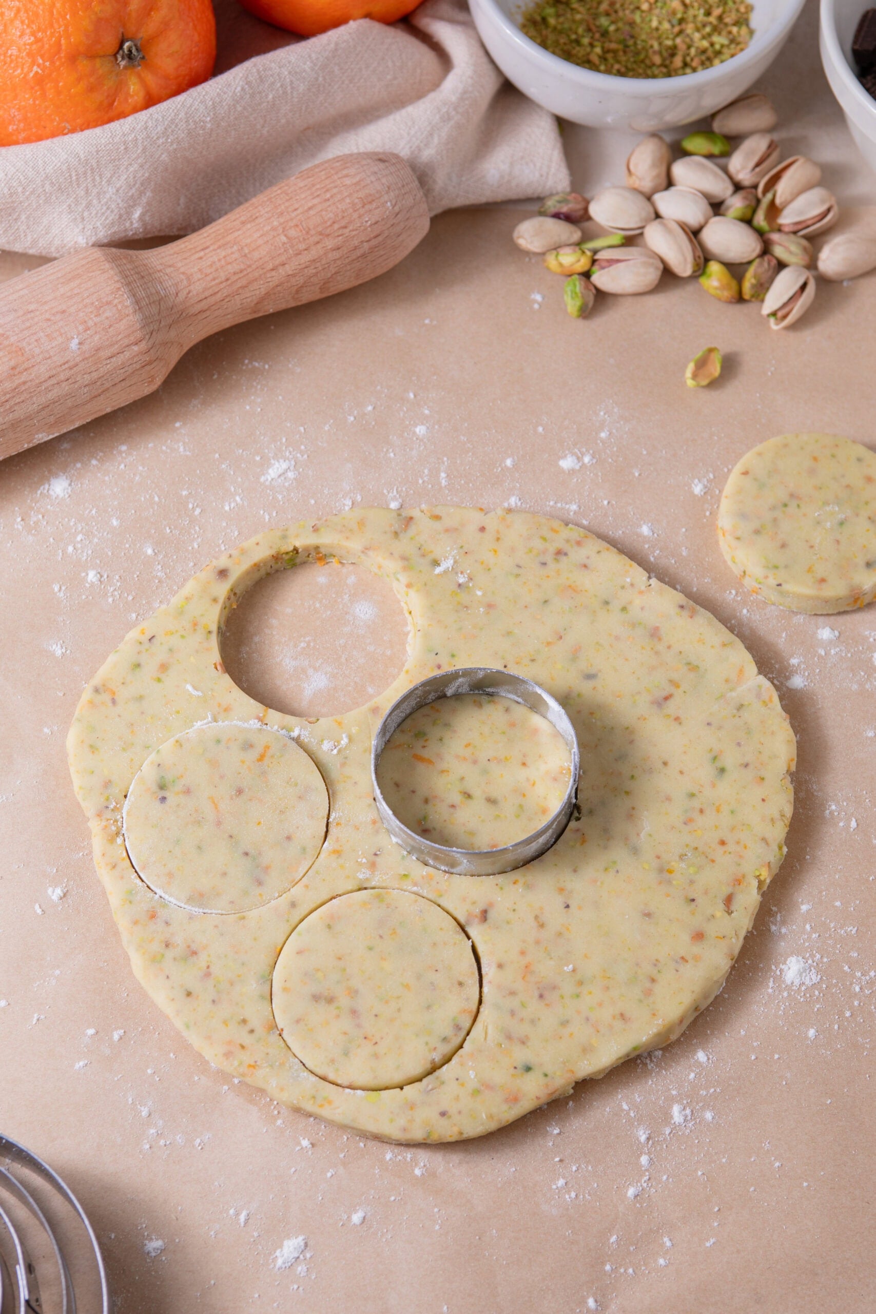 Rolling out orange pistachio shortbread cookie dough and cutting circles
