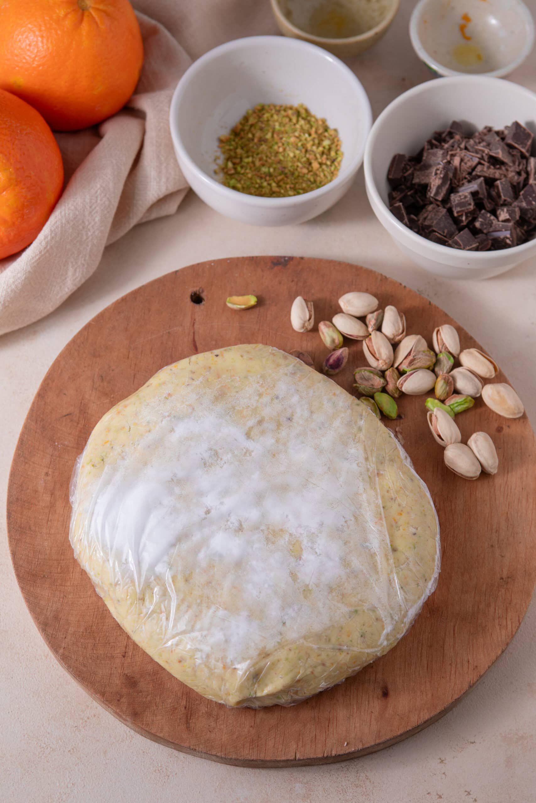Chilled orange pistachio shortbread cookie dough wrapped in plastic wrap
