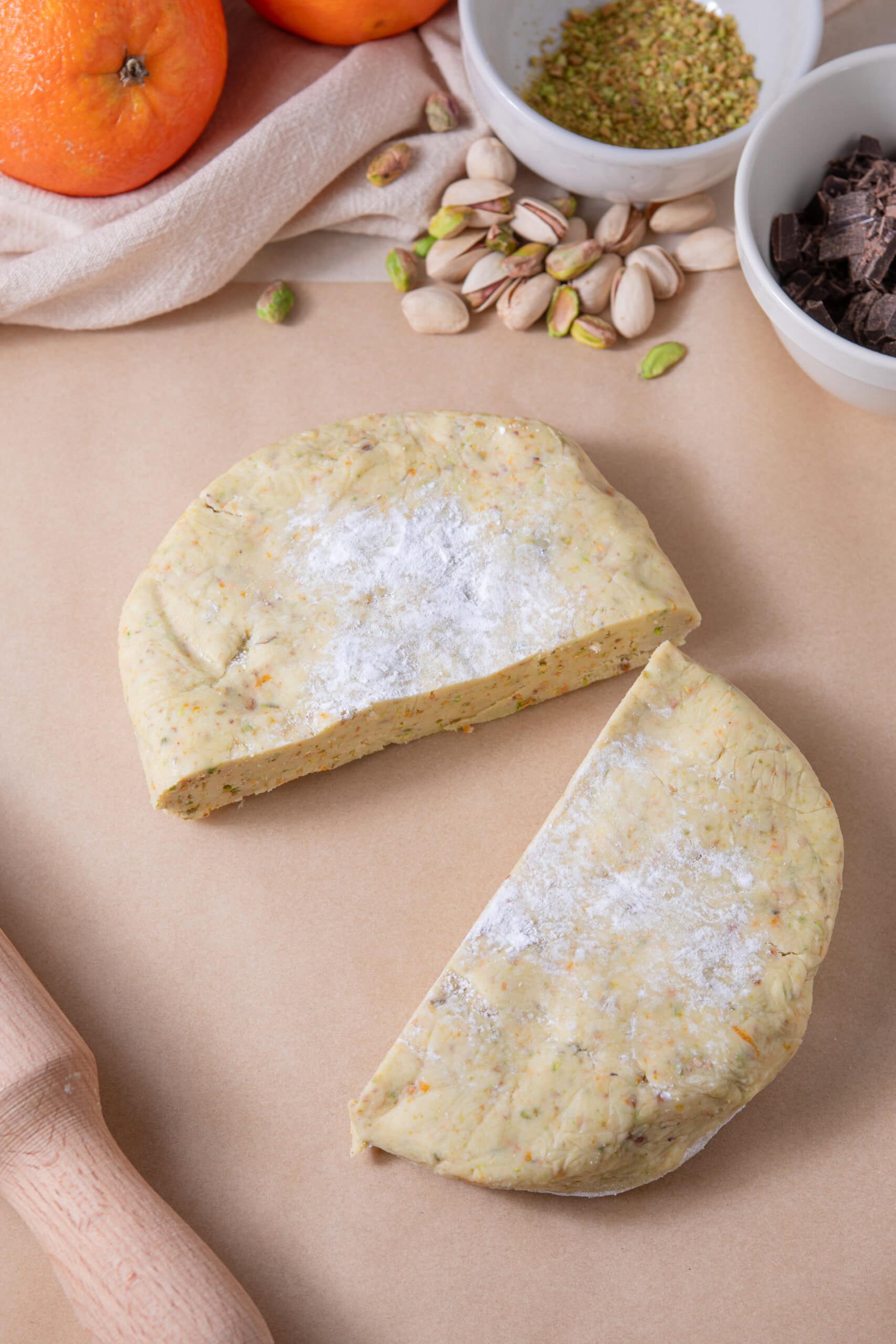 Unbaked pie dough on a baking surface with pistachios and chocolate in the background.